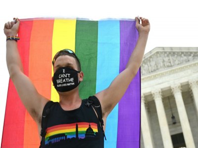 Un homme brandit un drapeau arc-en-ciel devant la Cour suprême, à Washington, le 15 juin 2020 - JIM WATSON [AFP]