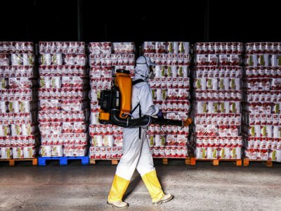 Un homme désinfecte des produits entreposés à  Curitiba, au Brésil, le 19 uin 2020 - DANIEL CASTELLANO [AFP]
