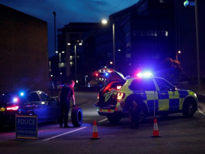 Des policiers changent le pneu d'un véhicule à un barrage près d'un parc où s'est produite une attaque meurtrière au couteau, à Reading le 20 juin 2020 - Adrian DENNIS [AFP]
