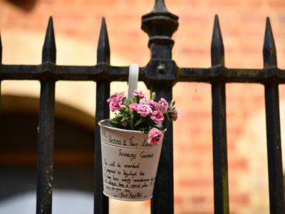 Des fleurs en hommage aux victimes sont accrochées à une grille le 21 juin 2020 à Reading, ville à une soixantaine de km de Londres, près d'un parc où s'est produite la veille une attaque meurtrière au couteau - Ben STANSALL [AFP]