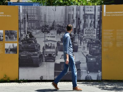 Le 22 juin 2020 à Berlin, devant un panneau portant une photo de Checkpoint Charlie du temps de l'Allemagne de l'Est et de l'Allemagne de l'Ouest - John MACDOUGALL [AFP]