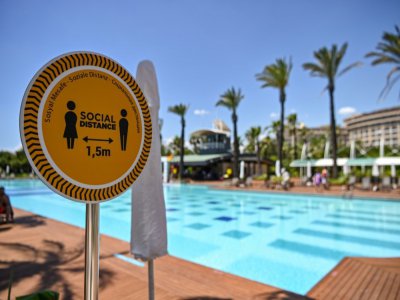 Un panneau invite au respect des distances physiques près de la piscine d'un hôtel à Antalya, dans le sud de la Turquie, le 19 juin 2020 - Ozan KOSE [AFP]