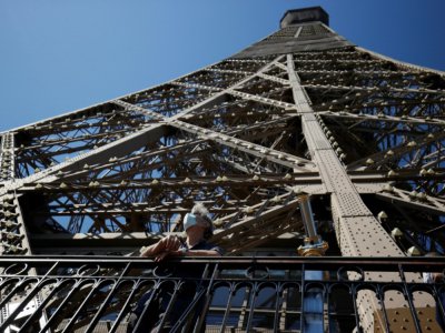 Un visiteur, le visage masqué pour se protéger du coronavirus, admire la vue depuis la Tour Eiffel qui rouvre partiellement après trois mois de fermeture, à Paris le 25 juin 2020 - Thomas SAMSON [AFP]