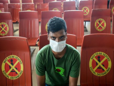 Un passager assis au milieu de sièges sur lesquels sont collés des avertissements à maintenir les distances comme mesure de protection contre le coronavirus, à l'aéroport international Hazrat Shahjalal de Dacca le 25 juin 2020 - MUNIR UZ ZAMAN [AFP]