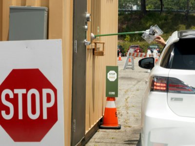 Un automobiliste reçoit un kit de prélèvement pour un test au coronavirus, le 25 juin 2020 à Los Angeles - VALERIE MACON [AFP]
