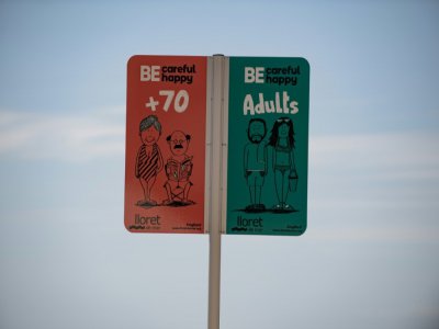 Un panneau indique les espaces réservés aux diffférents âges sur la plage de Lloret de Mar, le 22 juin 2020 en Espagne - Josep LAGO [AFP]