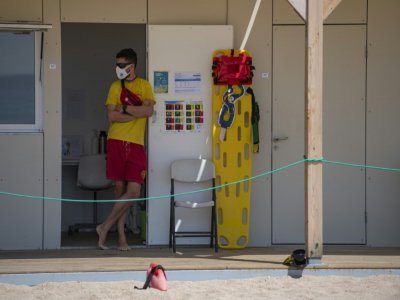 Un secouriste porte un masque de protection et surveille la plage de Lloret de Mar, le 22 juin 2020 en Espagne - Josep LAGO [AFP]