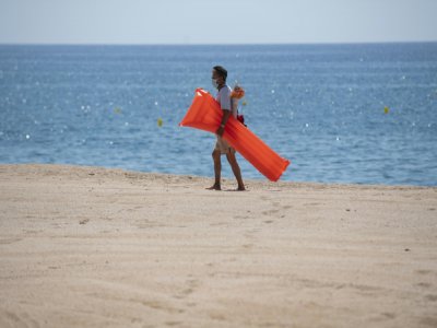 Un vacancier porte un masque de protection sur la plage de Lloret de Mar, le 22 juin 2020 en Espagne - Josep LAGO [AFP/Archives]