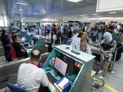 Des voyageurs masqués font la queue aux comptoirs d'enregistrement, le 27 juin 2020 à l'aéroport de Tunis - FETHI BELAID [AFP]