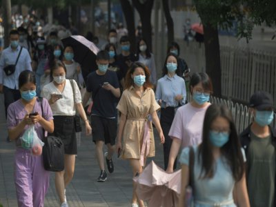 Des Chinois portent des masques de protection contre le coronavirus dans une rue de Pékin, le 28 juin 2020 - GREG BAKER [AFP]