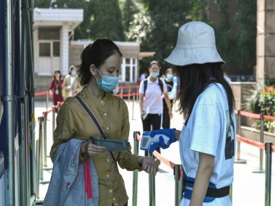 Contrôle de température avant d'entrer dans un établissement scolaire pour une élève qui va passer le bac à Nanjing, le 7 juillet 2020 - STR [AFP]
