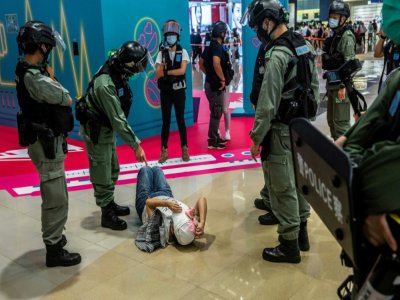 Un policier sermonne une jeune femme qui a été fouillée lors d'une manifestation contre la nouvelle loi imposée par la Chine,  à Hong Kong, le 6 juillet  2020 - ISAAC LAWRENCE [AFP]