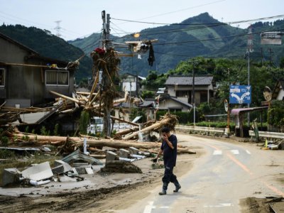 Un homme passe devant des décombres après des pluies torrentielles et des inondations dans le village de Kuma au Japon, le 8 juillet 2020 - CHARLY TRIBALLEAU [AFP]