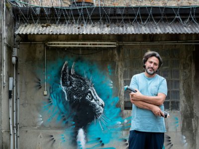 Le graffeur Christian Guemy, alias C215, pose à Fresnes devant une de ses oeuvres - JOEL SAGET [AFP]