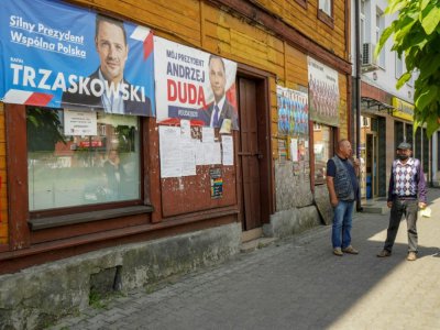 Deux hommes discutent devant des affiches de campagne des candidats du second tour de l'élection présidentielle polonaise le 9 juillet 2020 à Raciaz (Pologne) - JANEK SKARZYNSKI [AFP]