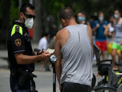 Un policier municipal effectue un contrôle du port du masque à Barcelone (Espagne) le 9 juillet 2020 - LLUIS GENE [AFP]