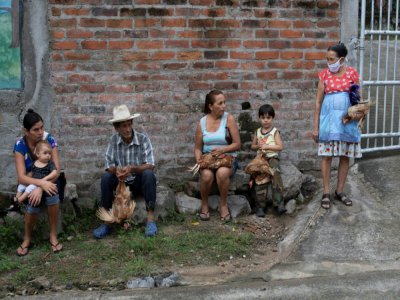 Des habitants tiennent des poules distribuées par des employés municipaux à des familles dans le besoin, à Sunapa (Salvador), le 2 juillet 2020 - Yuri CORTEZ [AFP]