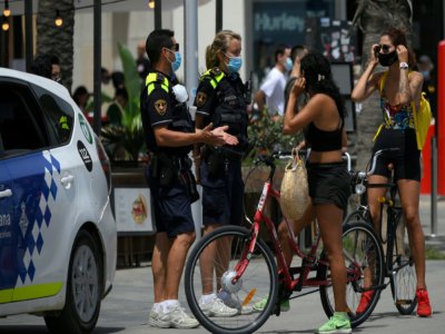 Des policiers municipaux demandent à des habitants de porter un masque de protection près d'une plage de Barcelone, le 9 juillet 2020 - LLUIS GENE [AFP]