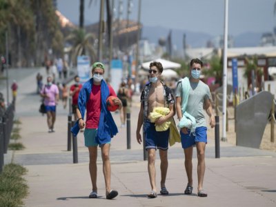 Des promeneurs avec les masques le long de la plage à Barcelone, le 18 juillet 2020 - Josep LAGO [AFP]