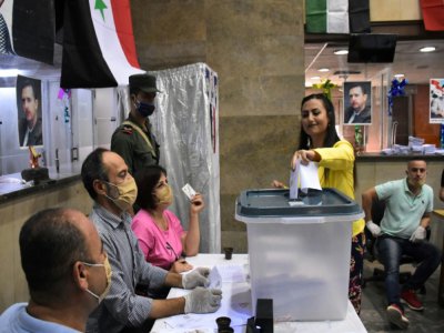 Une femme glisse son bulletin  dans un bureau de vote de la ville d'Alep, dans le nord de la Syrie, le 19 juillet 2020 à l'occasion des législatives syriennes - - [AFP]