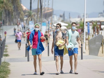 Des promeneurs avec les masques le long de la plage à Barcelone, le 18 juillet 2020 - Josep LAGO [AFP]