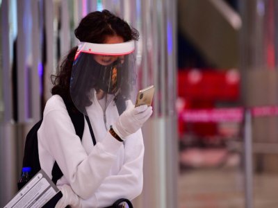 Une touriste consulte son téléphone en attendant un test de température à l'aéroport de Dubaï, le 8 juillet 2020 - GIUSEPPE CACACE [AFP/Archives]
