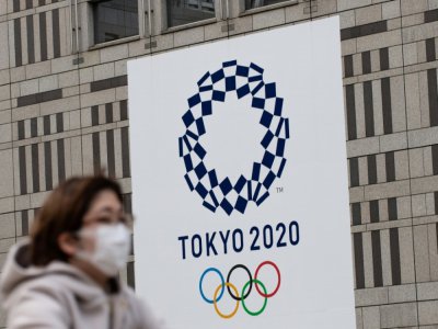 Une passante portant un masque, devant le logo des Jeux olympiques 2020, à Tokyo le 23 avril 2020 - Philip FONG [AFP/Archives]