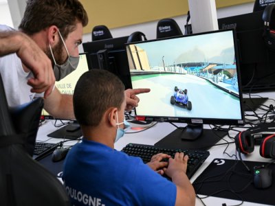 Un animateur donne des conseils à un enfant jouant à un jeu vidéo, le 22 juillet 2020 à Boulogne-Billancourt - BERTRAND GUAY [AFP]