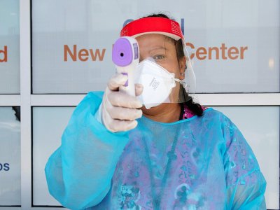 Un agent de santé tient un thermomètre sur un site de test du Covid-19 à St. John's Well Child and Family center à Los Angeles le 24 juillet 2020 - VALERIE MACON [AFP]