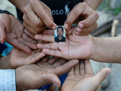Une veuve et ses cinq enfants montrent le 23 juillet 2020 une photo de leur époux et père, Joaquin Barrera, mort du Covid-19 comme ses parents et deux de ses frères à Santiago Nonualco, au Salvador - Yuri CORTEZ [AFP]