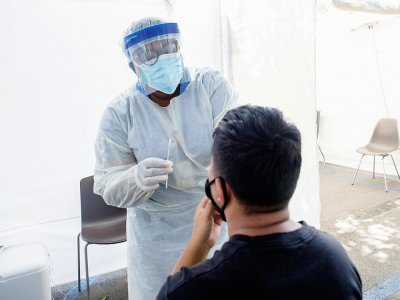 Un personnel médical prend un échantillon nasal d'un patient sur le site de John's Well Child à Los angles le 24 juillet - VALERIE MACON [AFP]