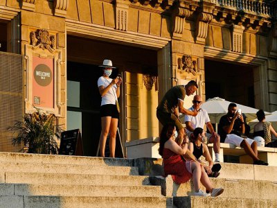 Des visiteurs assis devant le musée national d'art de Barcelone le 25 juillet 2020 - Pau BARRENA [AFP]
