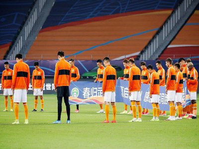 Les joueurs de Wuhan Zall lors d'une minute de silence en hommage aux victimes du Covid-19 lors de la reprise du championnat en Chine le 25 juillet 2020 - STR [AFP]