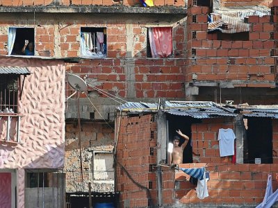 Un voisin salue avec un miroir Ruben Pena lors de son émission diffusée depuis le toit de son immeuble à Caracas, le 18 juillet 2020, destinée à égayer la vie des habitants - Federico PARRA [AFP]