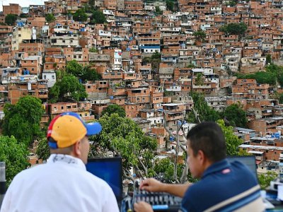 Ruben Pena (g) est avec son voisin Lino Borges, sur le toit de son immeuble à Caracas, le 18 juillet 2020 d'où il anime une "émission" transmise grâce à trois baffles pour égayer la vie des habitants - Federico PARRA [AFP]