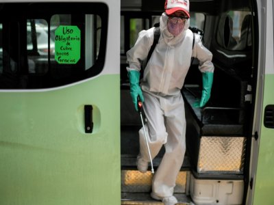 Un employé en équipement de protection désinfecte un autobus de transport en commun le 30 juillet 2020 à Mexico - PEDRO PARDO [AFP]