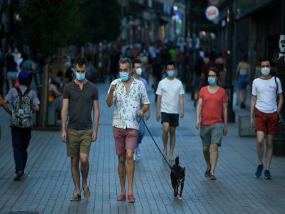 Des passants portant des masques obligatoires dans les lieux publics marchent dans le centre de Madrid le 30 juillet 2020 - PIERRE-PHILIPPE MARCOU [AFP]