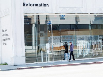 Une personne portant un masque passe devant un magasin fermé sur l'avenue Melrose à Los Angeles, le 3 août 2020 - VALERIE MACON [AFP]