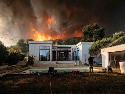 Un homme arrose sa maison pour la protéger d'un incendie à La Couronne, près de Marseille, le 4 août 2020 - Xavier LEOTY [AFP]