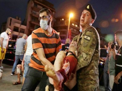 Un soldat libanais et un homme transportent un blessé à l'hôpital après les explosions le 4 août 2020 - IBRAHIM AMRO [AFP]