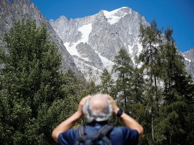 Un homme observe avec des jumelles le glacier de Planpincieux à Courmayeur, le 6 août 2020 au Val Ferret, en Italie - MARCO BERTORELLO [AFP]