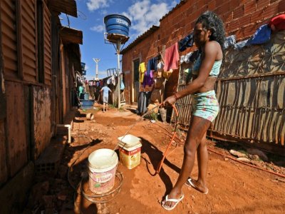 Une femme remplit des seaux d'eau dans une ruelle de Santa Luzia, près de Brasilia, le 3 août 2020 au Brésil - EVARISTO SA [AFP]