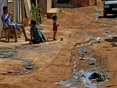 Des enfants jouent près d'un écoulement d'eaux usées dans une rue de Santa Luzia, près de Brasilia, le 3 août 2020 - EVARISTO SA [AFP]