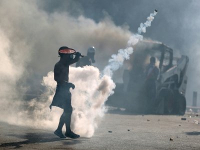Un manifestant utilise une raquette pour renvoyer une grenade lacrymogène lors de heurts avec la police, le 8 août 2020 à Beyrouth - PATRICK BAZ [AFP]