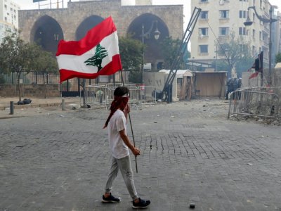 Un homme porte un drapeau libanais lors d'une manifestation, le 8 août 2020 à Beyrouth, pour demander des comptes à la classe politique après la terrible explosion ayant dévasté une partie de la capitale et fait plus de 150 morts - ANWAR AMRO [AFP]