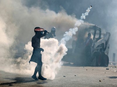 Un manifestant portant un masque utilise une raquette pour renvoyer les grenades lacrymogènes tirées par les forces de sécurité à Beyrouth, le 8 août 2020 - PATRICK BAZ [AFP]