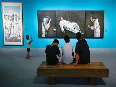 Des visiteurs parcourent l'exposition “L'union fait la force" sur le combat contre le Covid-19 qui présente notamment un tableau de l'artiste Pang Maokun, au musée national de Chine à Pékin le 5 août 2020 - STR [AFP]