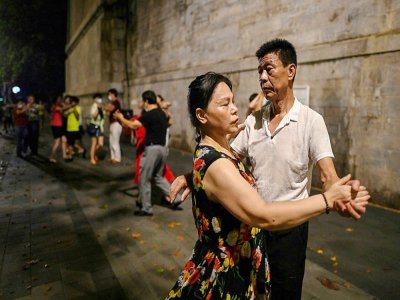 Des couples dansent dans la rue près de la rivière Yangtsé à Wuhan (Chine), le 5 août 2020 - Hector RETAMAL [AFP]