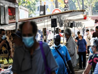 Des personnes portent un masque de protection au marché Ornano dans le 18e arrondissement de Paris, le 11 août 2020 - ALAIN JOCARD [AFP]