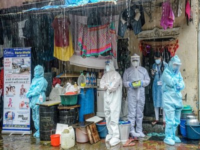 Des soignants en combinaison de protection s'abritent de la pluie à Bombay (Inde) le 12 août 2020 - INDRANIL MUKHERJEE [AFP]